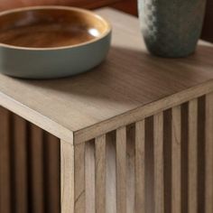 a bowl sitting on top of a wooden table next to a vase and potted plant