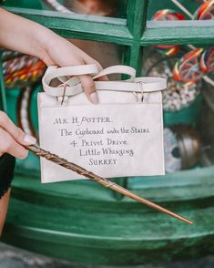 a person holding a harry potter bag with a wand in it's handle and writing on the back