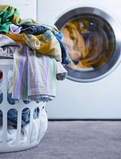 a laundry basket filled with clothes next to a washing machine