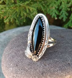 Stunning Vintage Sterling Silver Native American Black Onyx Ring. This is a beautiful ring, with long diamond Shaped Black Onyx Stone. lt is set in a sawtooth Bezel setting. With a Sterling Silver flower and Leaf design. Absolutely a beautiful piece to add to your Native American Jewelry collection. This piece is stamped Sterling on the inside of band. Ring Size is 7. Weight measures 0.153 In Troy Ounces Weight Measures 4.76 In Grams. Measures 1 3/16" Long by 1/2" Wide. It will be packaged in a Black Southwestern Jewelry With Turquoise Accents, Black Southwestern Concho Jewelry, Southwestern Black Concho Jewelry, Vintage Native American Jewelry, Black Onyx Stone, Flower Leaf, Black Onyx Ring, Garnet Earrings, Sterling Silver Flowers