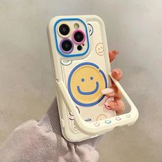 someone holding up their phone case with a smiley face painted on the front and sides