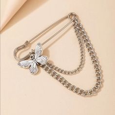 a silver butterfly brooch with chain attached to it's clasps on a beige background