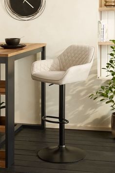 a modern bar stool in front of a clock on the wall