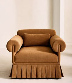 a brown chair with ruffles on the back and arms, in front of a white wall