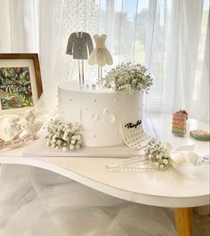 a white wedding cake with flowers on the top and two bride's dresses hanging from it