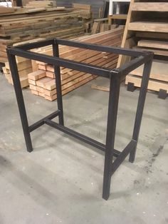 a metal frame sitting on top of a floor next to stacks of wooden planks