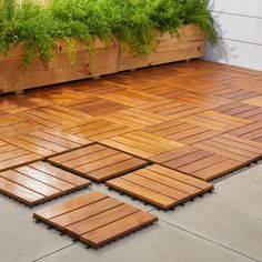 several wooden boards laid out on the ground in front of a planter with green plants