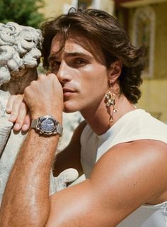 a young man leaning against a statue with his hand on the arm and looking at the camera