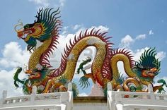 two colorful dragon statues on top of a white building with blue sky in the background