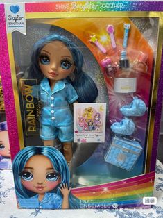 the doll has blue hair and is next to its box with it's contents