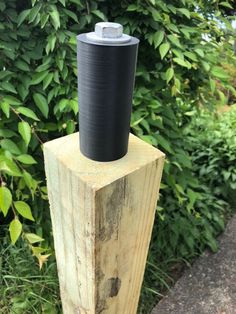 a wooden post with a black cylinder on top