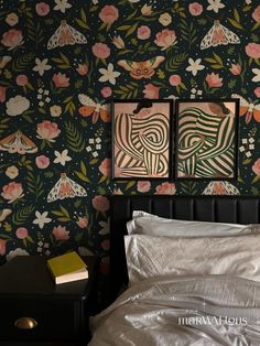 two paintings on the wall above a bed in a room with floral wallpaper and white sheets