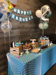 a blue table topped with lots of desserts and balloons