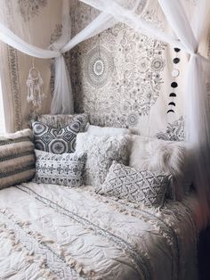 a bed with pillows and blankets on top of it in front of a curtained window