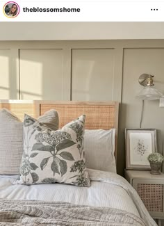 a bed with two pillows on top of it next to a night stand and lamp