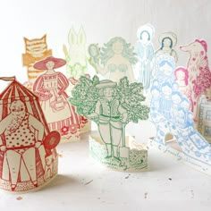 paper cut out of children's dresses and hats on a white table with other items