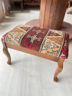 a small wooden bench with a colorful rug on it's back end and legs