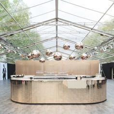 the inside of a tent with several tables and lights on each side in front of it