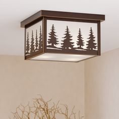 a ceiling light with trees cut out of it's sides and the lights are on