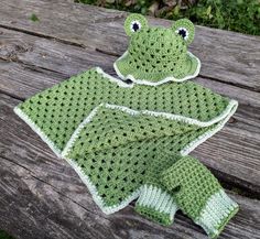 a crocheted frog hat and diaper cover sitting on a wooden bench