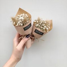 two small flowers are wrapped in brown paper