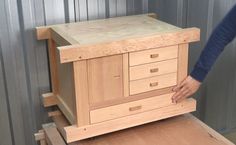 a person standing next to a wooden cabinet on top of a piece of plywood