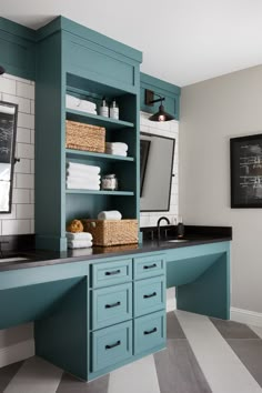 a bathroom with blue cabinets and black counter tops, white tile flooring and gray walls