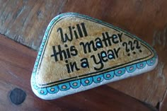 a rock with the words will this matter in a year? on it sitting on top of a wooden table