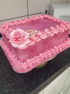 a cake with pink frosting and flowers on it sitting on top of a counter