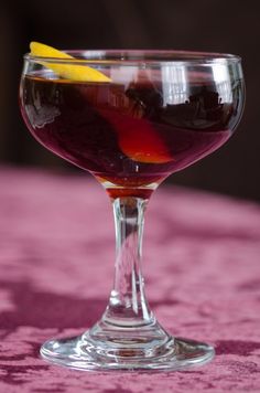 a glass filled with liquid sitting on top of a pink table cloth covered tablecloth