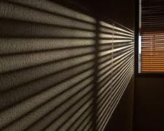 the light is shining through the blinds on the wall in the room that has it's shadow