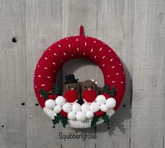 a knitted wreath with two owls sitting on top of it next to a wooden fence