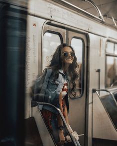 a woman sitting on a subway train looking out the window with her hand in her pocket