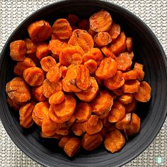 a black bowl filled with cooked carrots on top of a table