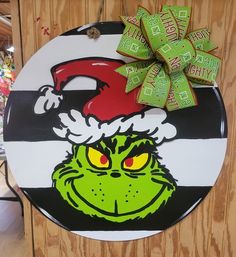 the grin face has been painted on a round sign with a green ribbon and is wearing a santa hat