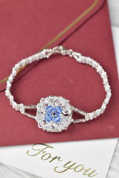 a bracelet with a blue flower on it sitting next to a card that says for you