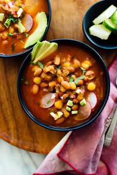 two bowls filled with beans and avocado on top of a wooden cutting board