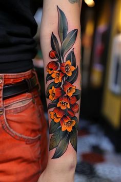 a woman's arm with orange flowers on it and green leaves around the wrist