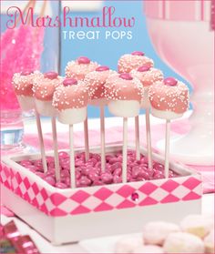 pink and white desserts in a box on a table with marshmallow treats