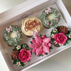 cupcakes in a box decorated with flowers and the words happy christmas written on them