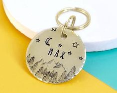 a metal keychain with the word max on it and trees in the background