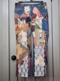 an old pair of jeans with patchwork and lace on them hanging from a door