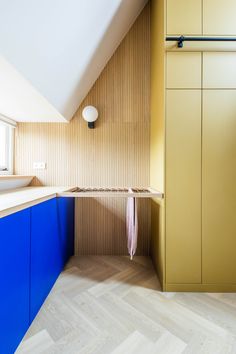 an attic bathroom with blue and yellow cabinetry, wood flooring, and white walls