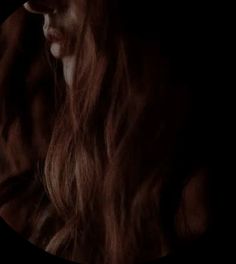 a woman with long hair standing in the dark