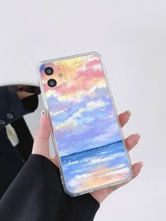 a woman holding up her phone case with an ocean scene painted on it