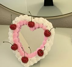 a cake shaped like a heart with cherries in the shape of a heart on a table