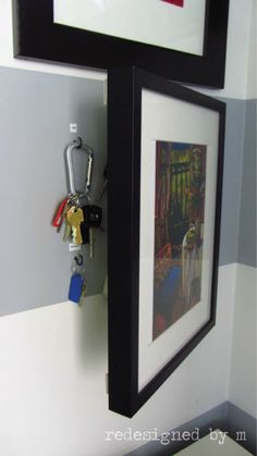 two framed pictures hang on the wall next to a key rack with keys in it