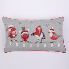 a gray pillow with red and white birds on it's sides, wearing christmas hats