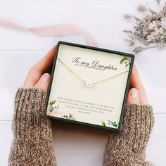 a person holding a necklace in their hand with a card attached to the box that says, for my daughter