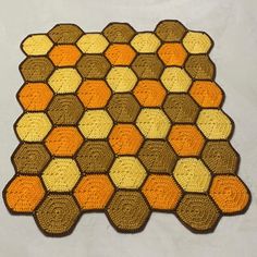 an orange and brown rug with hexagons on it's sides, sitting on a white surface